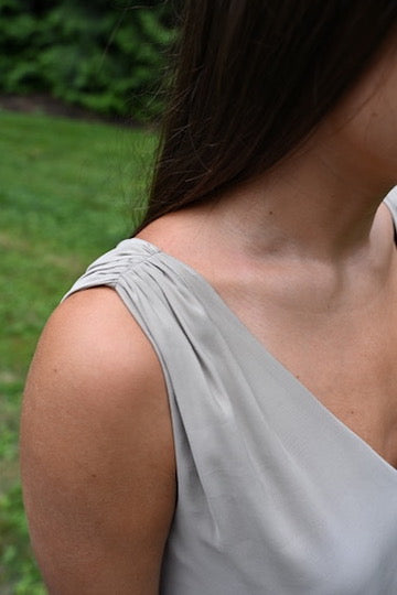 Close-up of a woman wearing a sand PKTS Kelley dress, featuring the shirred shoulder construction.