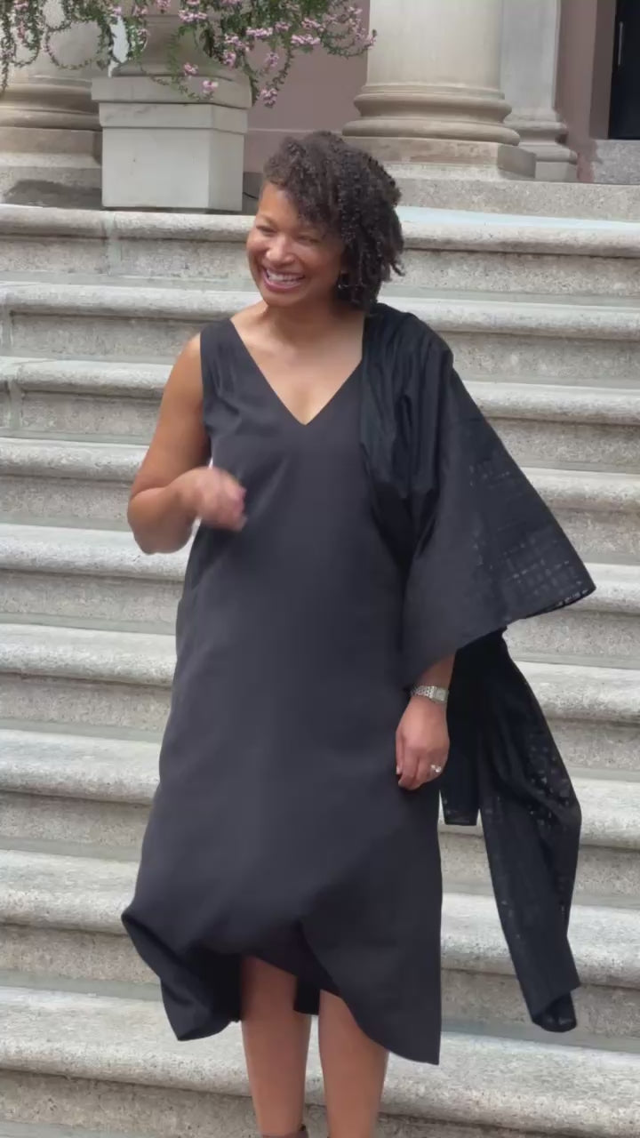 A video of Kelley wearing the PKTS midi Kelley dress in black with a one-sleeve Karami-ori cloth wrap on the steps of an historic building